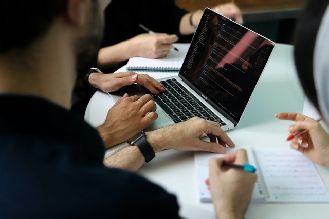 B2B marketing team reviewing website copy together around a laptop in a professional office